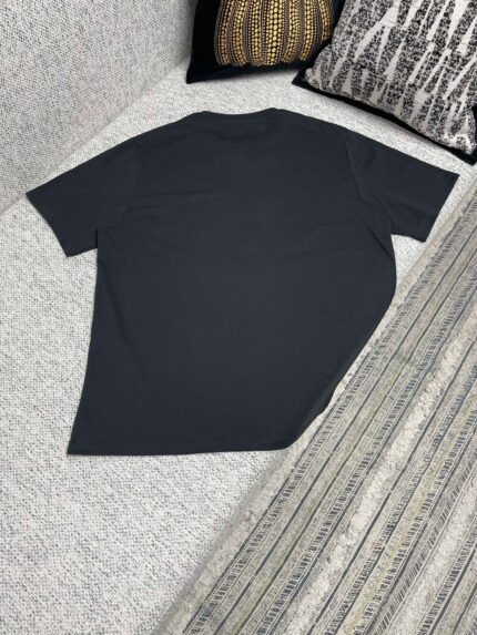 Maglietta navy casual su superficie morbida con cuscini e tessuto a righe.
