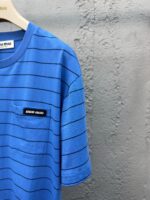 Maglietta casual a righe blu con patch nero, ideale per look estivi e rilassati.