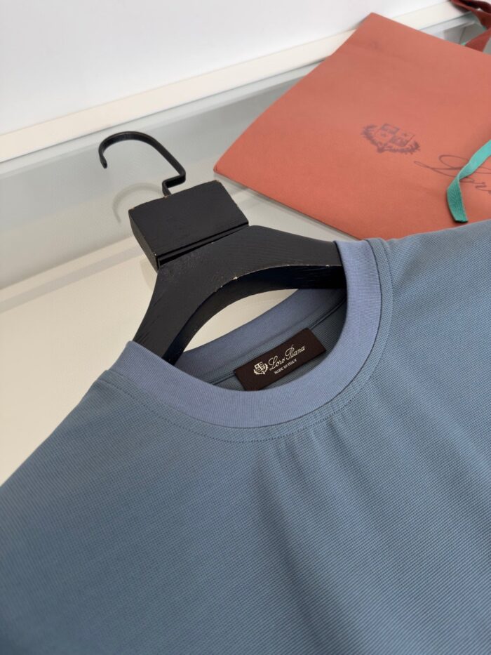 Felpa blu casual con collo a coste, su gruccia nera e sfondo terracotta elegante.