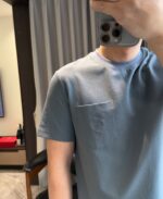 Selfie in casa con maglietta blu chiara, stile casual e ambiente luminoso e accogliente.