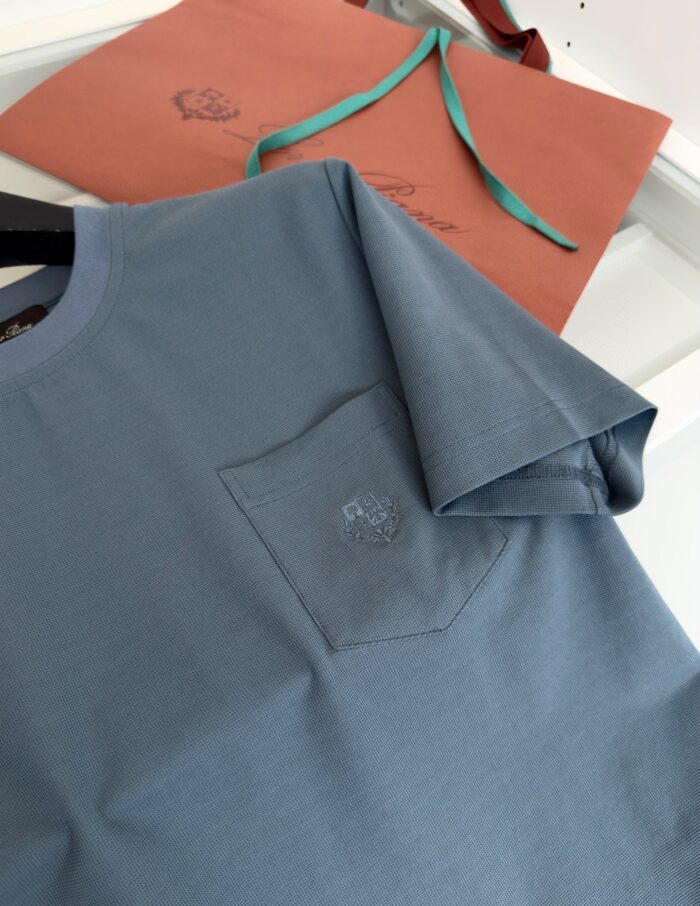 Maglietta casual blu chiaro con tasca ricamata, elegante sacchetto regalo corallo e nastro teal.