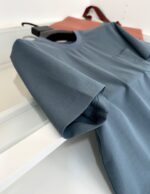 T-shirt blu chiaro casuale con taschino, accompagnata da borsa marrone, stile semplice e alla moda.