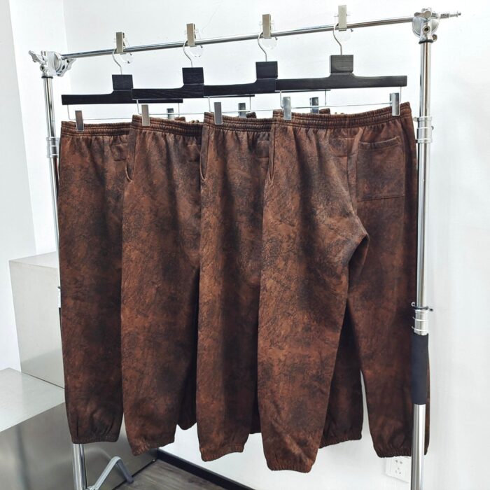 Pantaloni casual in similpelle marrone con texture mottled, stile minimalista, perfetti per ogni occasione.