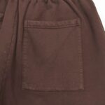 Taschino in tessuto marrone scuro su pantaloni casual, dettagli eleganti e pratici.