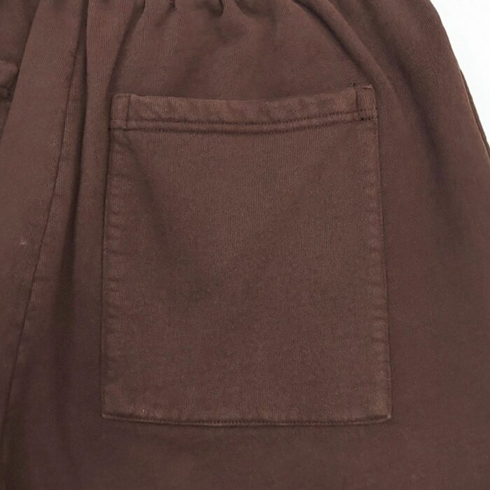 Taschino in tessuto marrone scuro su pantaloni casual, dettagli eleganti e pratici.