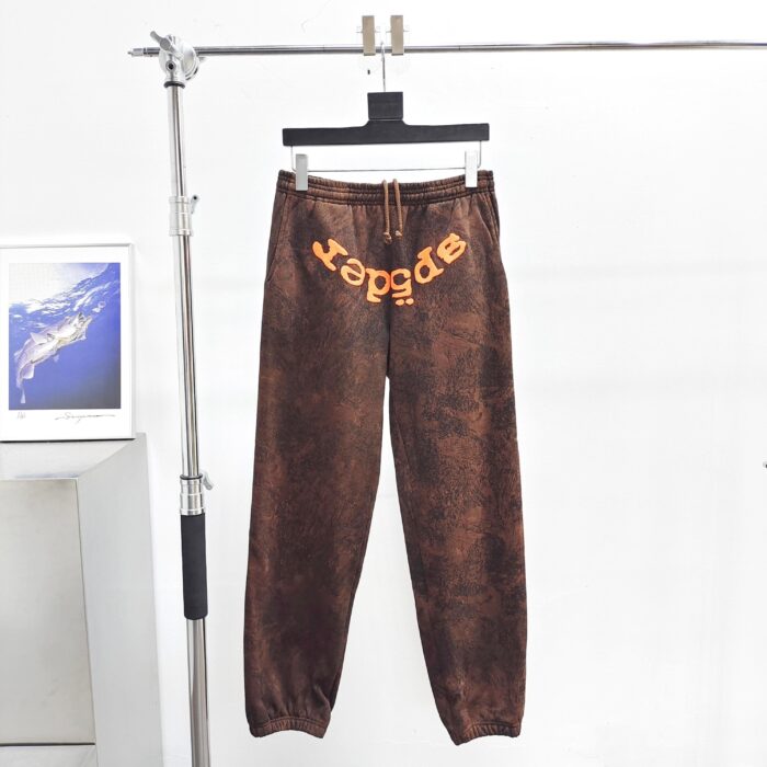 Pantaloni jogger marroni con logo arancione, streetwear trendy e comodo, su rastrelliera moderna.