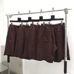 Pantaloncini marroni casual con perforazioni artistiche, tasca laterale, stile moderno e pratico.