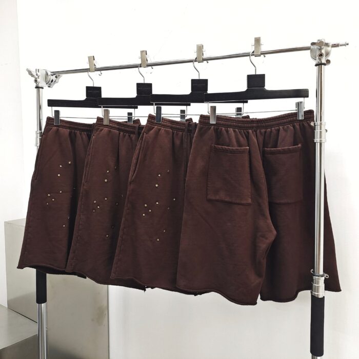 Pantaloncini marroni casual con perforazioni artistiche, tasca laterale, stile moderno e pratico.