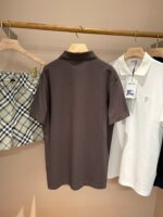 Esposizione di polo, shorts a quadri e abbigliamento casual su supporto in legno.