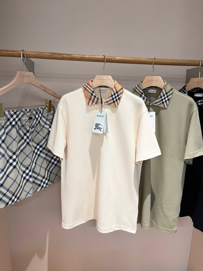 Display moda casual estate con shorts scozzesi e polo in tonalità neutre su grucce di legno.