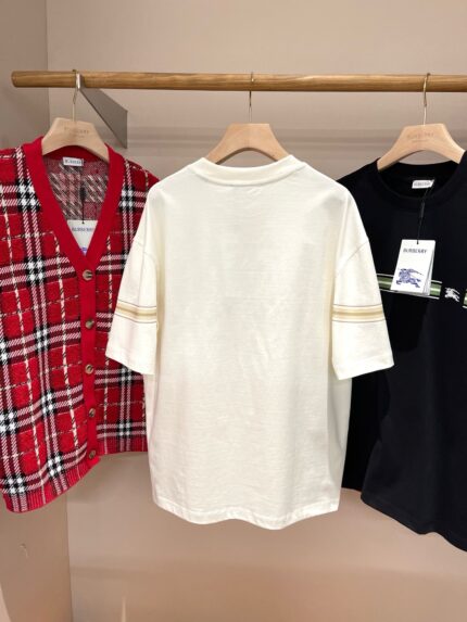Esposizione di cardigan a quadri, T-shirt bianco e camicia nera in negozio di moda casual.