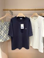 Vetrina con abbigliamento casual: shorts a quadri e T-shirt blu e bianca su scaffale di legno.