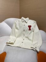 Camicia crema con cuore rosso, dettaglio elegante su sedia moderna, stile casual e raffinato.