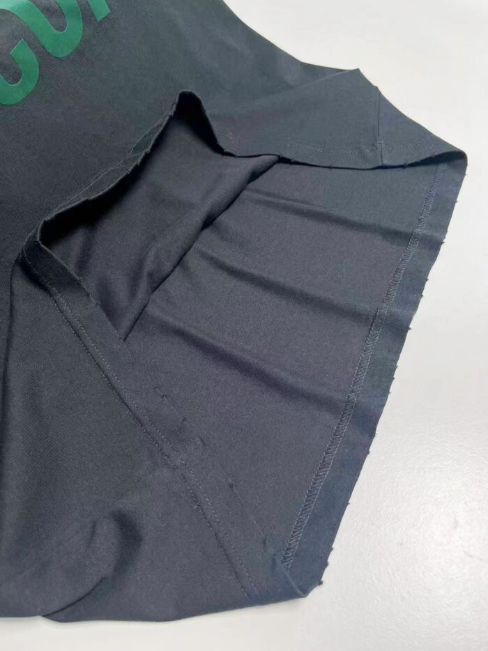 Maglia nera con polsino arrotolato e dettaglio verde, stile moderno e di qualità.