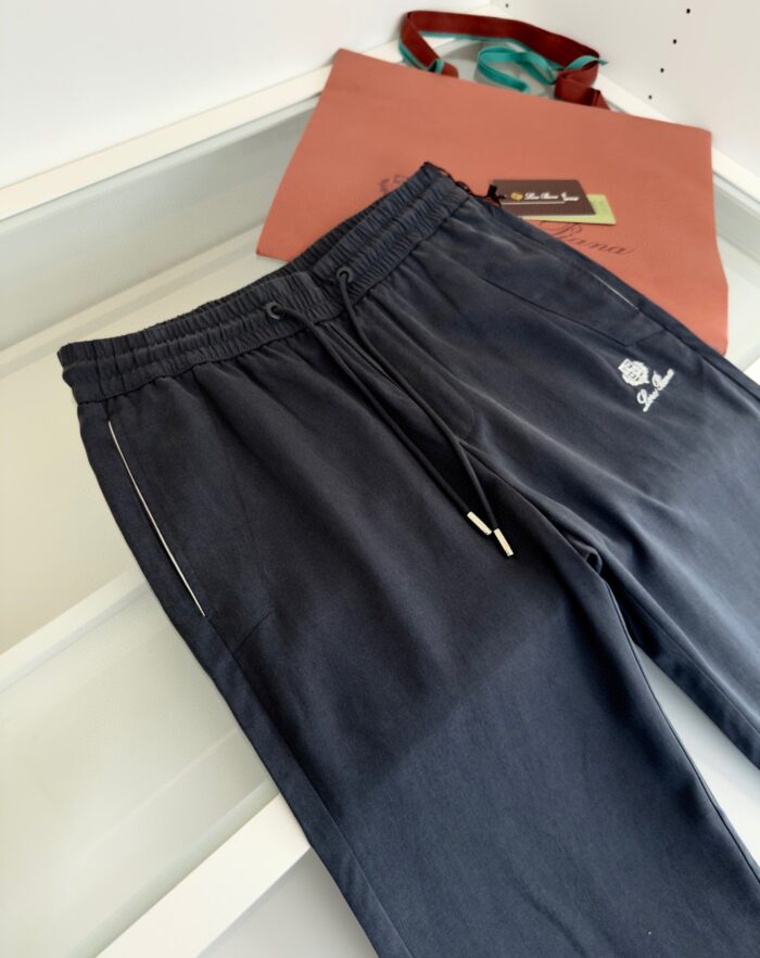 Pantaloni jogger scuri con logo, tasche metallizzate e borsa tote colorata per look casual.