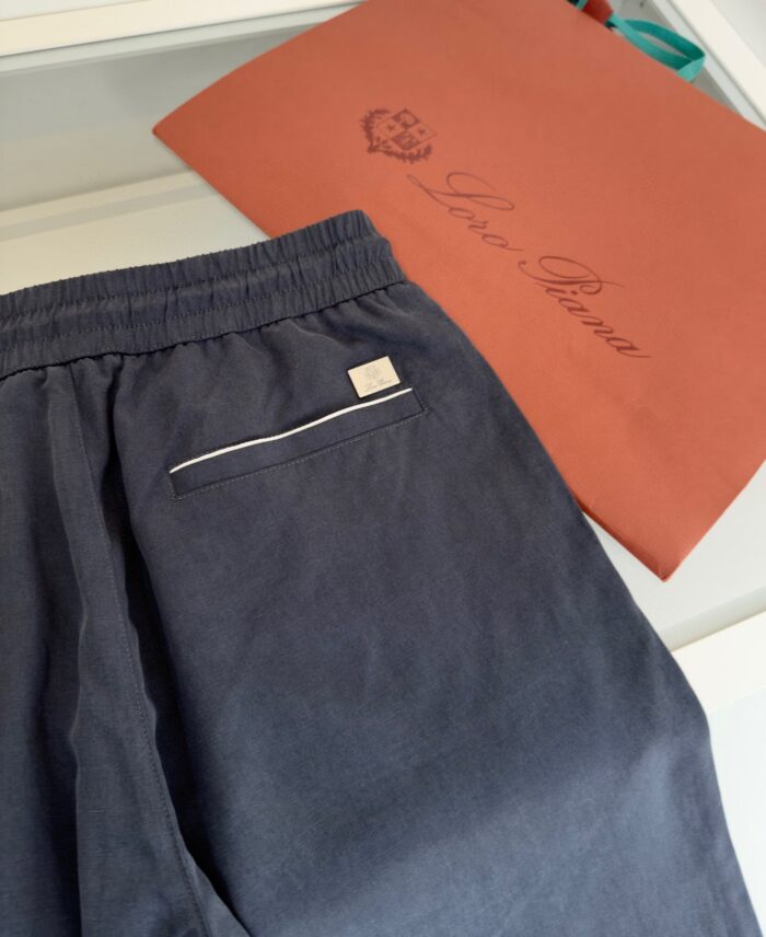 Pantaloncini casual in tessuto leggero con dettagli bianchi, accompagnati da borsa Loewe arancio bruciato.