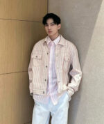 Uomo in stile casual elegante con giacca di jeans e camicia a righe, sfondo neutro beige.