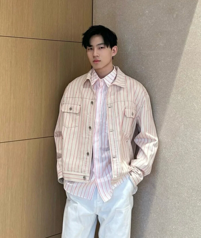 Uomo in stile casual elegante con giacca di jeans e camicia a righe, sfondo neutro beige.