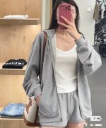 Donna con outfit casual in negozio, scatta selfie davanti allo specchio, stile comodo e alla moda.