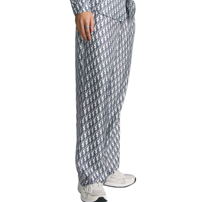 Completo casual blu e bianco con pantaloni larghi, camicia geometrica e sneakers bianche.