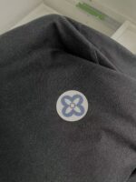 Felpa casual con logo floreale blu su sfondo bianco, design elegante e confortevole.