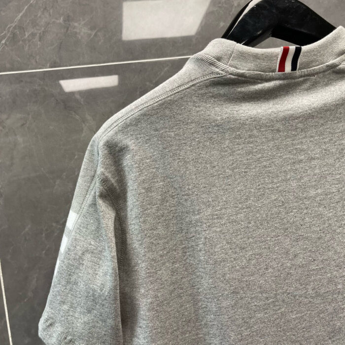 Maglietta polo grigia con colletto classico e dettagli a contrasto, stile casual e sportivo.