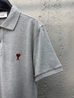 Maglietta polo grigia con logo ricamato a cuore rosso, stile casual e versatile.