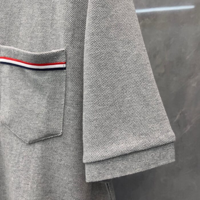 Camicia casual grigia con tasca a strisce colorate, stile rilassato e dettagli eleganti.
