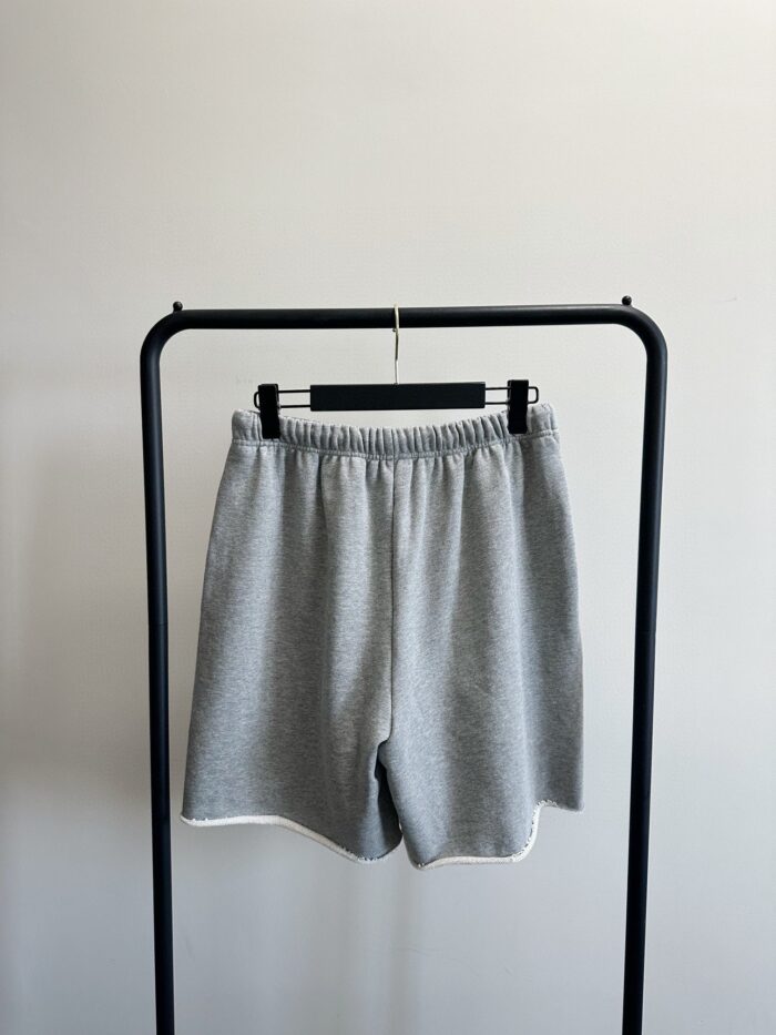 Pantaloncini sportivi grigi eleganti su esposizione minimalista, ideali per casual e allenamento.