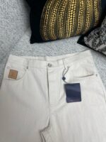 Jeans chiari moderni con dettagli eleganti su sfondo con cuscino nero e oro.