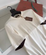 T-shirt crema elegante con dettagli burgundy e tote bag naturale, stile daily chic raffinato.
