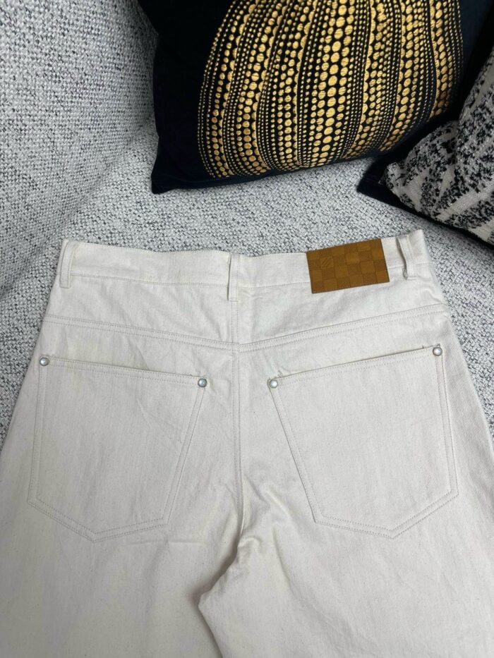 Jeans chiari a vita alta su divano elegante con tasche e patch in pelle.