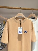 Maglietta beige con grafica blu, stile casual e dettagli moderni in boutique elegante.