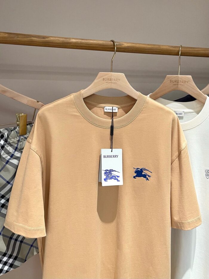 Maglietta beige con grafica blu, stile casual e dettagli moderni in boutique elegante.