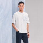 Uomo giovane in stile casual con T-shirt bianca e pantaloni navy, look moderno e rilassato.