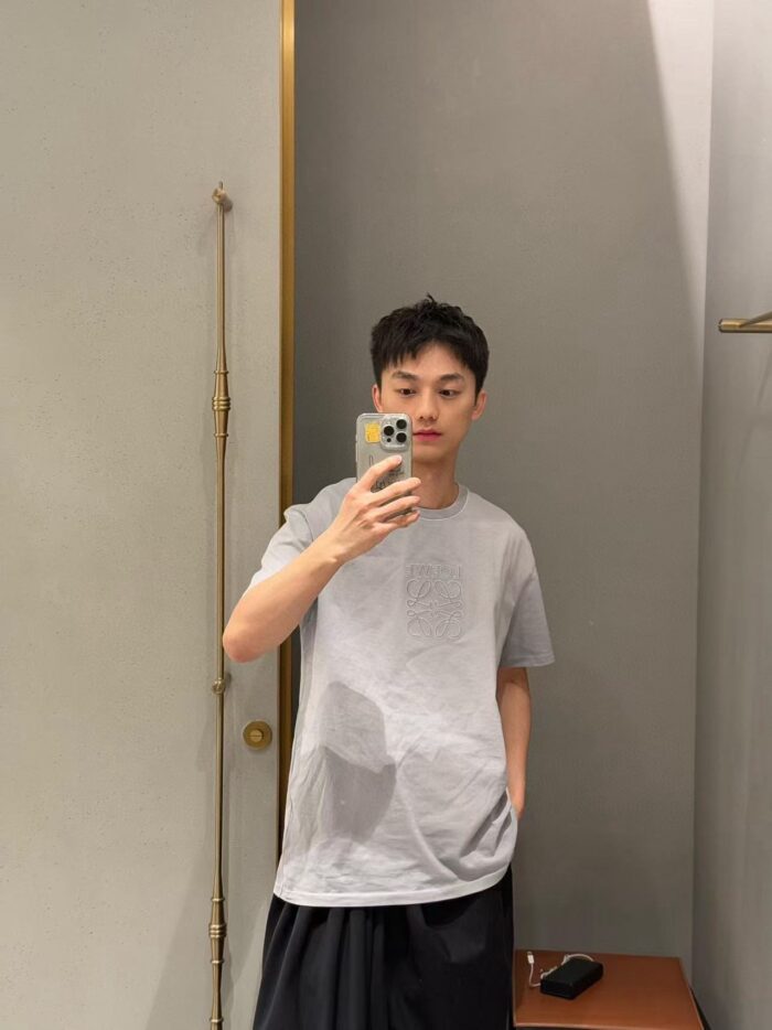 Giovane uomo casual mentre si scatta un selfie in ambiente minimalista, stile rilassato e moderno.
