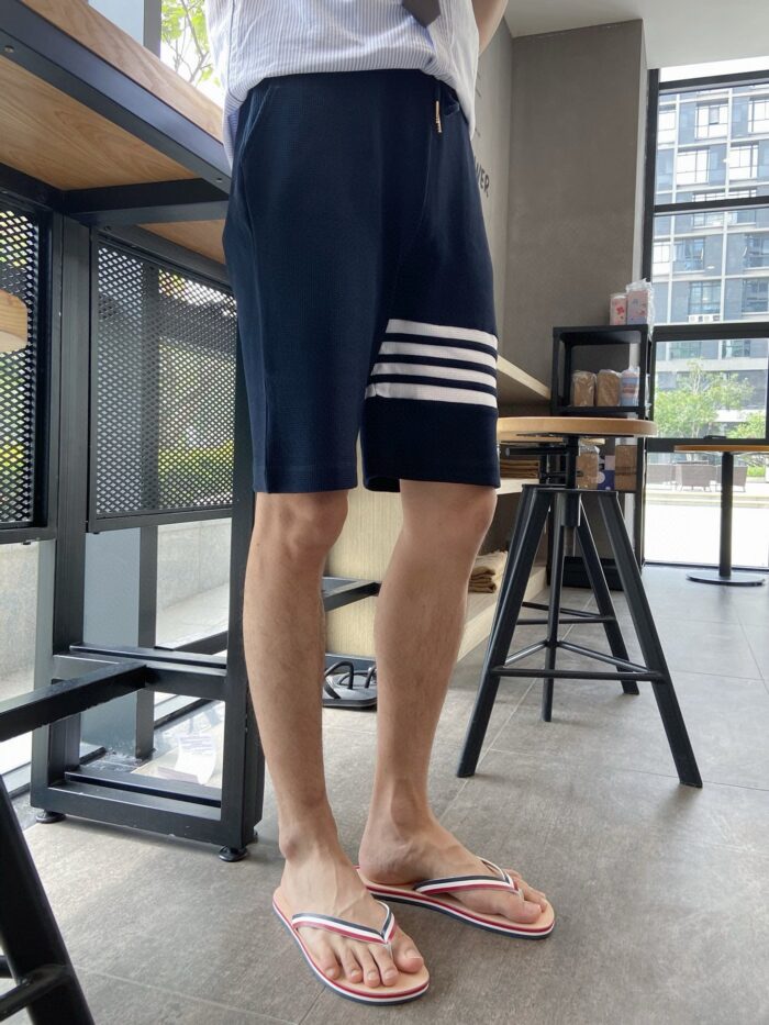 Uomo in shorts e flip-flops in ambiente moderno e luminoso, stile casual e rilassato.