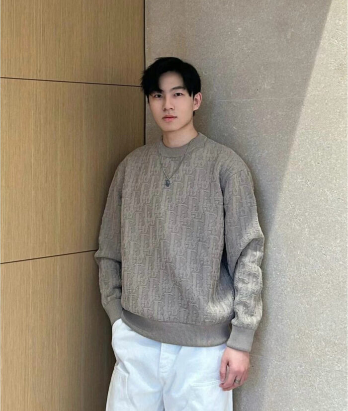Uomo elegante in stile casual modern con sweater oversize e pantaloni bianchi in ambiente luminoso.
