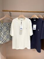Set di abbigliamento casual minimalista con t-shirt crema, navy e gonna a quadri neutra.