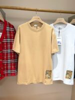 Set di abbigliamento casual: T-shirt beige e bianca con dettaglio, cardigan rosso a quadri.