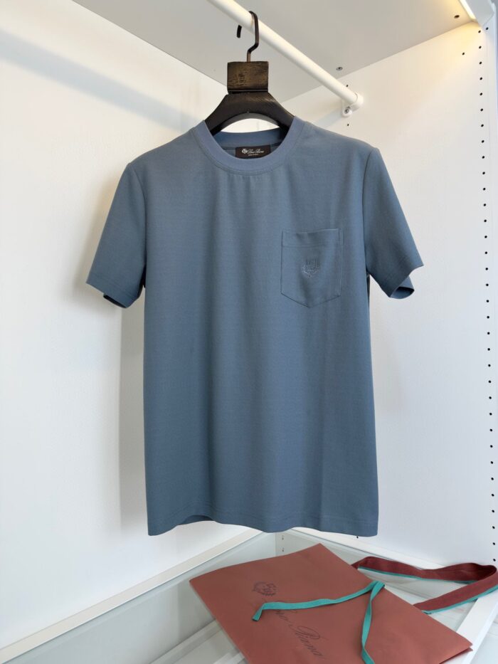 T-shirt blu menta casuale con taschino, stile minimalista e versatile, su sfondo bianco naturale.