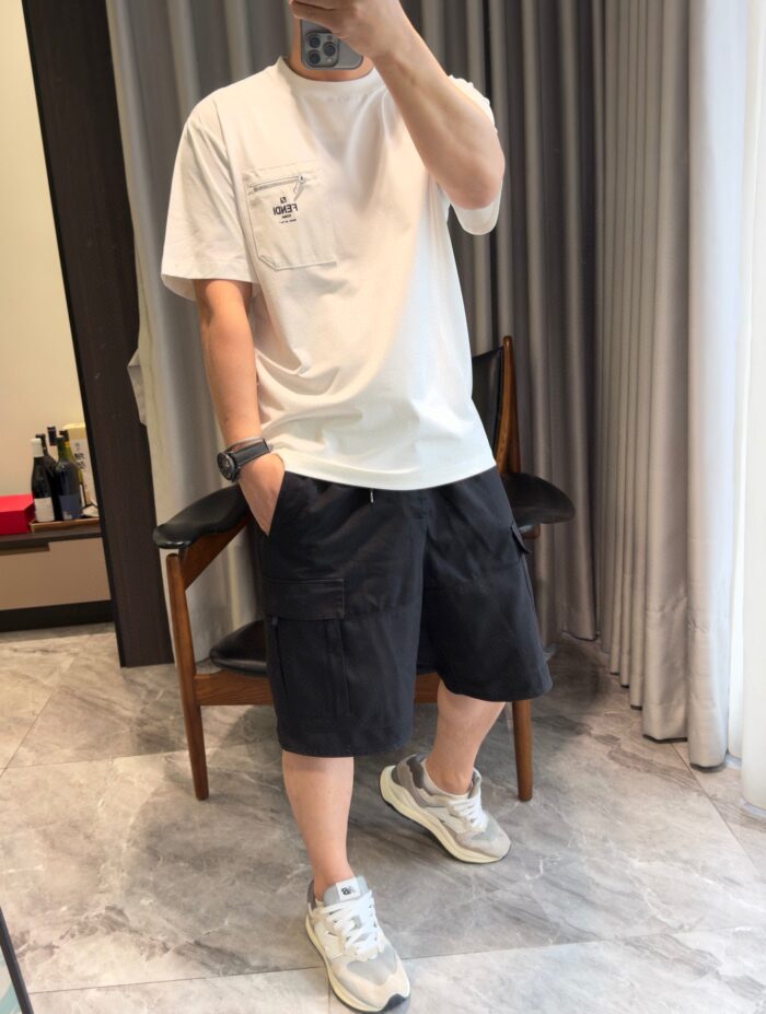 Donna in outfit casual con t-shirt, shorts scuri e sneakers bianche in bagno con specchio.