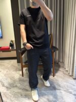 Persona in stile casual moderno con jeans scuri e sneakers bianche in ambiente interno elegante.