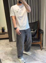 Look elegante casual con jeans, sneakers bianche e stile moderno in interni minimalisti.