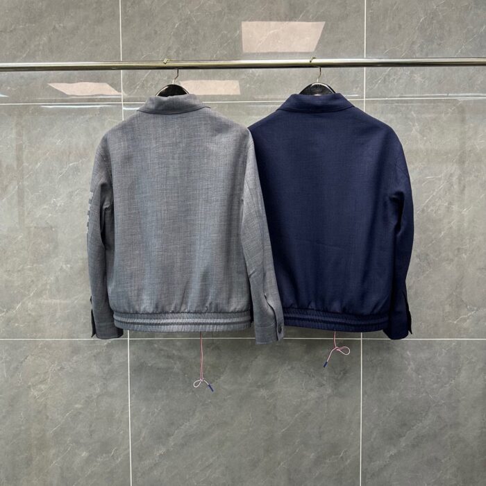 Giacche sportive navy e grigia su appendiabiti in ambiente minimalista e moderno.