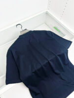 Maglietta nera semplice in cotone su appendiabiti, perfetta per outfit casual e minimalisti.