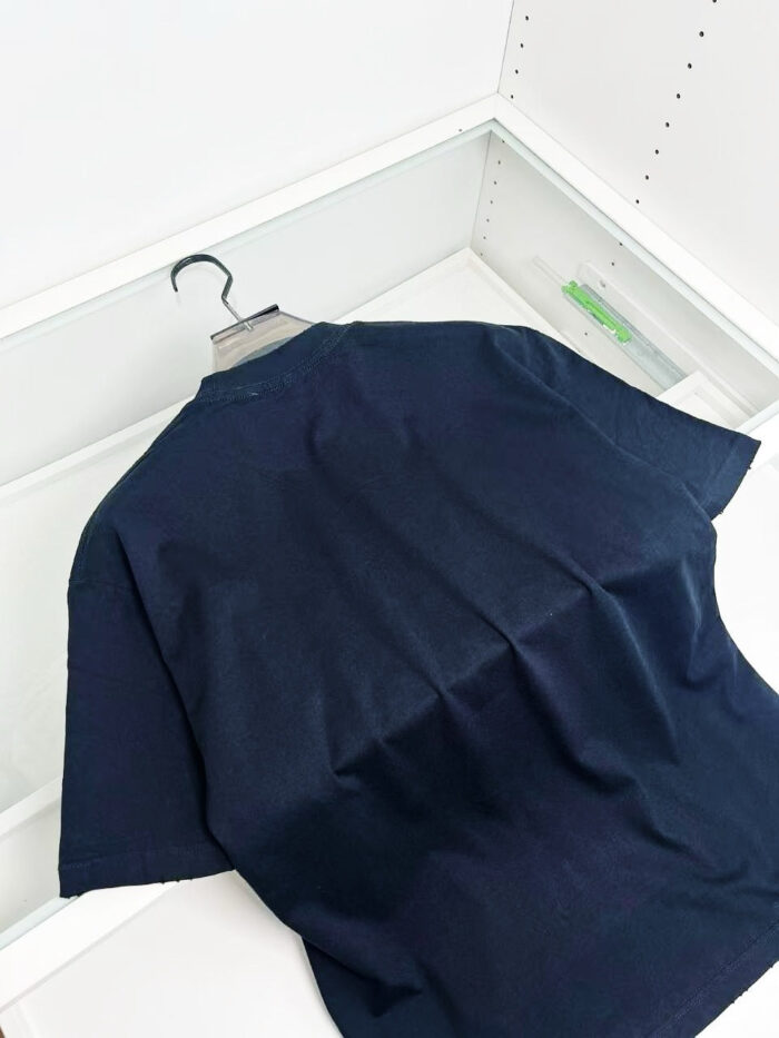 Maglietta nera semplice in cotone su appendiabiti, perfetta per outfit casual e minimalisti.