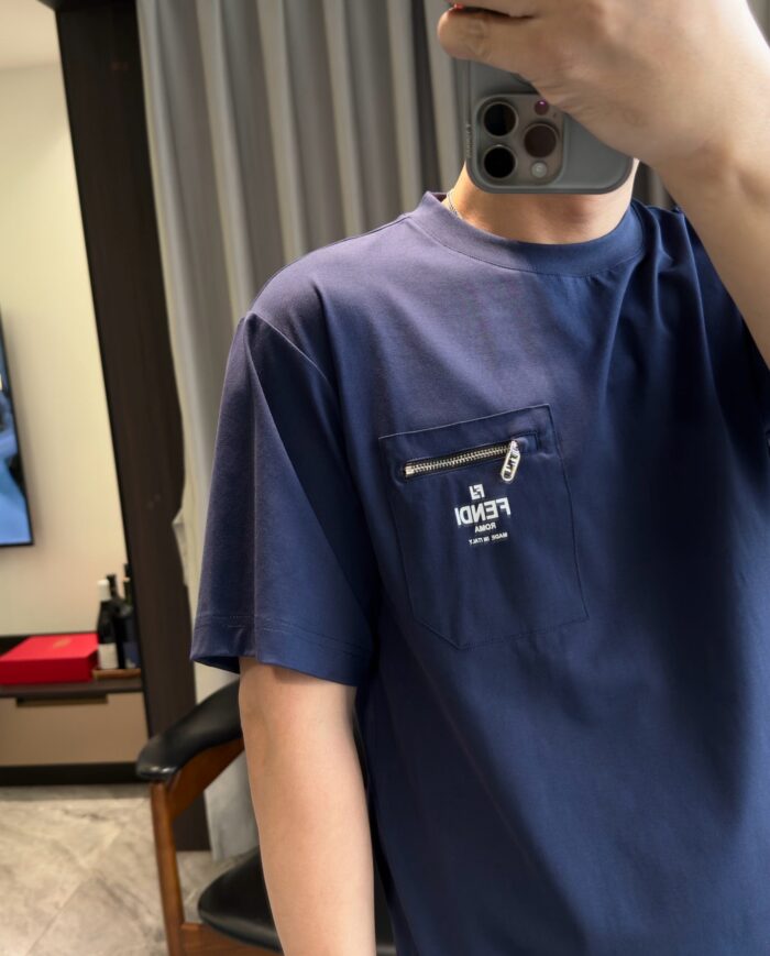 Maglietta navy casual con taschino e selfie in ambiente moderno e minimalista.