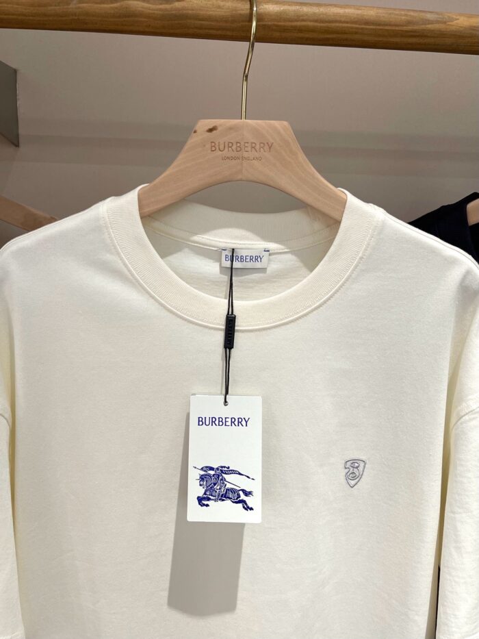 Camicia Burberry off-white a manica lunga, logo ricamato blu, stile elegante e casual.