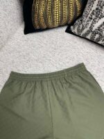 Pantaloni verdi oliva casual, decorazioni home cozy con cuscini eleganti e tessuti morbidi.